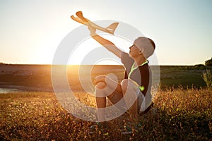 boy sitting at sunset with an airplane in his hand