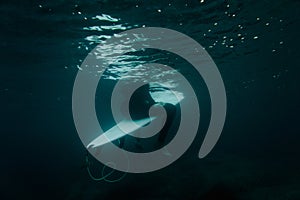 Boy sitting on the surf board on the line up under the water