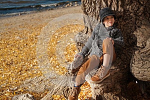 Boy sitting on the tree at the beach