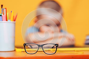 Boy sitting ubfocused glasses in focus. Concept problem of ophthalmology correction of myopia. back to school. Selective focus.