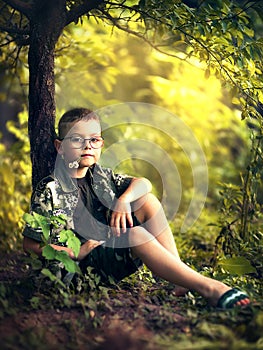 Boy sitting under a tree in the forest