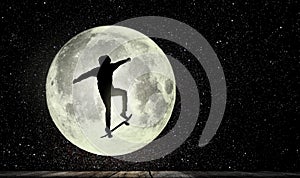 Boy on the skateboard jumps, in the background the full moon