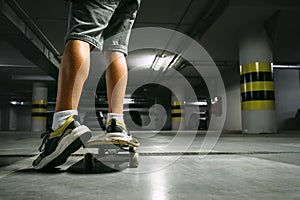 Boy on skateboard skates in undeground parking close up image