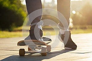 Boy skater in a summer park. legs feet of man in fashionable jeans and stylish sneakers on a skateboard longboard