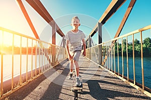 Boy skates on skate board on the bridge over tthe river photo