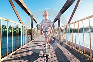 Boy skates on skate board on the bridge over tthe river photo