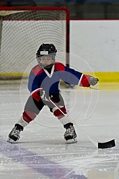 Boy skating backwards while practicing ice hockey