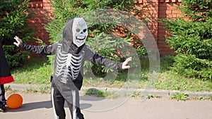 boy in skeleton costume dances on street. Halloween prepare to collect candy . Trick-or-treating. Guising. Jack-o