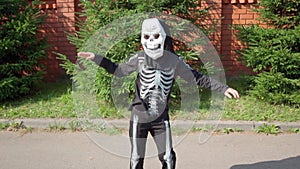 boy in skeleton costume dances on street. Halloween prepare to collect candy . Trick-or-treating. Guising. Jack-o