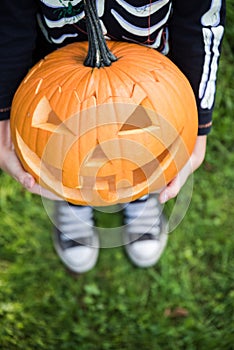 Boy in skeleton costume holding pupmkin