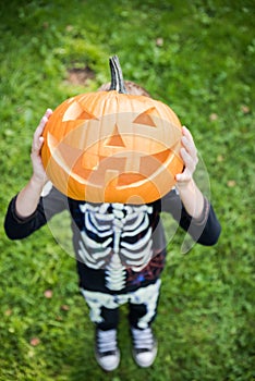 Boy in skeleton costume holding pupmkin