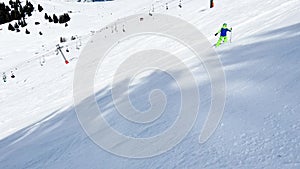 Boy ski fast downhill on alpine track view from behind