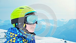 Boy in ski gear with goggles showing reflections of mountain peaks