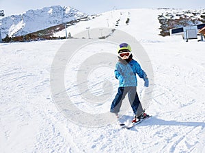 Boy in ski mask learns skiing on snow downhill