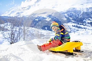 Boy on sled ride. Child sledding. Kid on sledge