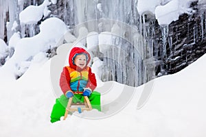 Boy on sled ride. Child sledding. Kid on sledge