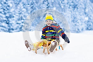 Boy on sled ride. Child sledding. Kid on sledge