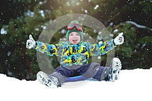 Boy sledding in a snowy forest. Outdoor winter fun for Christmas vacation.