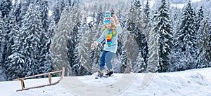 Boy sledding on winter mountain, enjoying a sledge ride in a beautiful snowy winter park. Winter landscape banner.