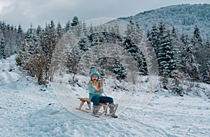 Boy sledding on winter mountain, enjoying a sledge ride in a beautiful snowy winter park. Winter scene with snowy forest