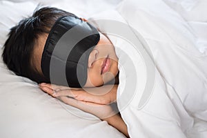 Boy sleeping on bed white pillow and sheets with sleep mask