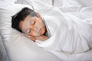 Boy sleeping on bed with white sheet and pillow