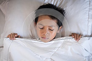 Boy sleeping on bed with white sheet and pillow