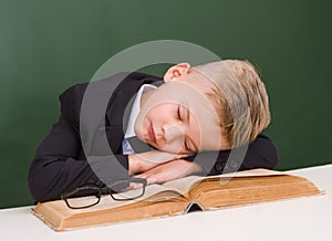 Boy sleeping on book in classroom