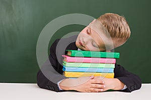 Boy sleeping on books in classroom