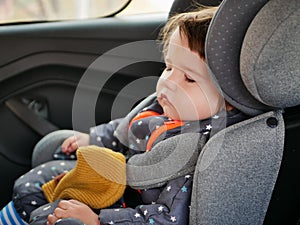 The boy is sleeping in a car seat. Driving safety for the child. 0-1 year old baby sleeping in a car seat