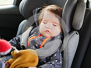 The boy is sleeping in a car seat. Driving safety for the child. 0-1 year old baby sleeping in a car seat