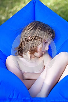 Boy Sleeping in an Inflatable Plastic Lounger.