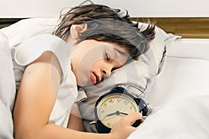 Boy sleeping peacefully and holding an alarm clock