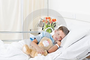 Boy sleeping with teddy bear in hospital