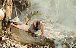 The boy is sleeping, waiting for the fish he grilled. Happily After finding it at a stream near his house In the rural areas of