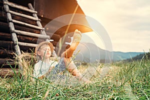 Boy sleeps in grass under hayloft in summer afternoon photo