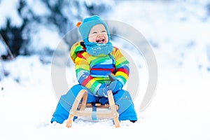 Boy on sleigh ride. Child sledding. Kid with sledge