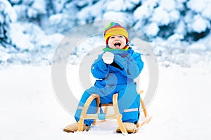 Boy on sleigh ride. Child sledding. Kid with sledge