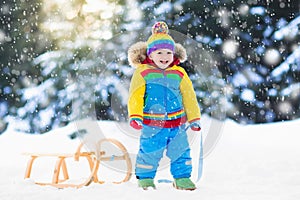 Boy on sleigh ride. Child sledding. Kid with sledge