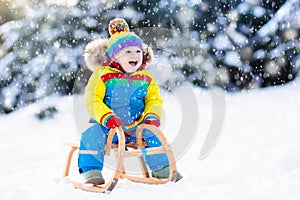 Boy on sleigh ride. Child sledding. Kid with sledge