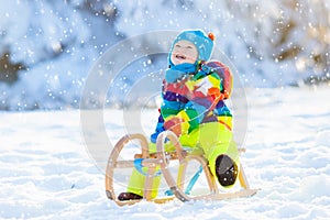 Boy on sleigh ride. Child sledding. Kid with sledge