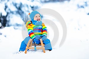 Boy on sleigh ride. Child sledding. Kid with sledge