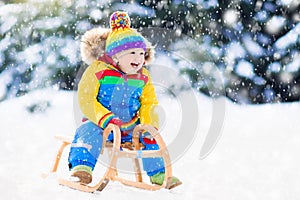 Boy on sleigh ride. Child sledding. Kid with sledge