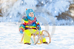 Boy on sleigh ride. Child sledding. Kid with sledge