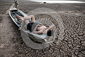 The boy slept on a fishing boat and placed his hands on the forehead on the dry floor,global warming