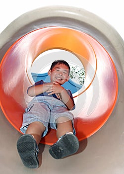 Boy sliding down on a cylindric slide