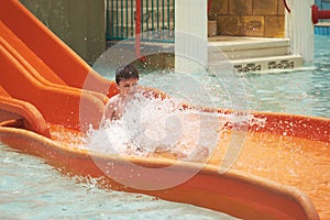 Boy sliding down slide in waterpark.