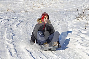 Boy sliding down snow hill on sled outdoors in winter, sledging and season concept