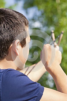 Boy with a slingshot aim to the tree