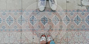 boy with slippers and girl with sandals on pink colored tile
